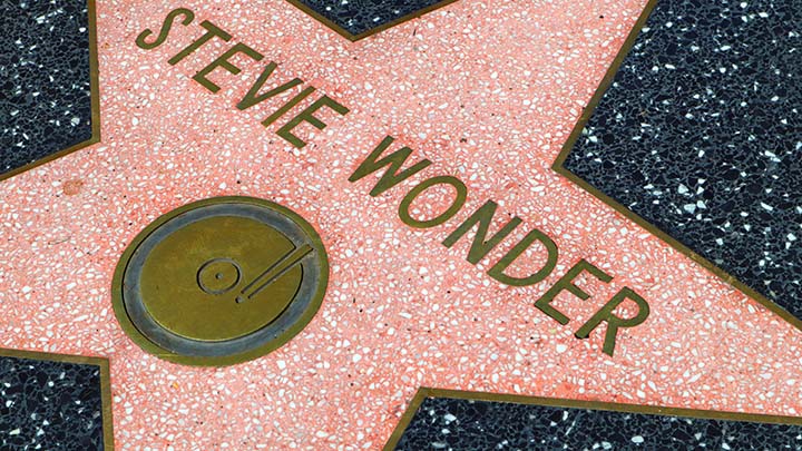 A closeup of a star on the Hollywood Walk of Fame bearing the name of Stevie Wonder. It has the symbol for re3cording artists, a platter with a tone arm over it.